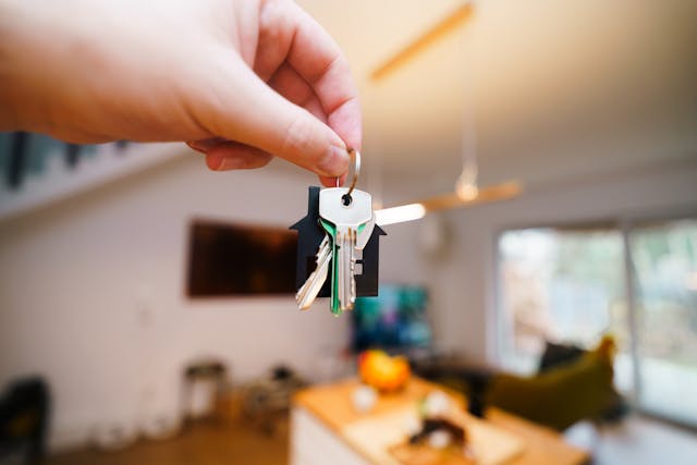 person holding up house keys while in a living room